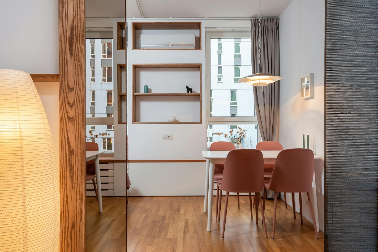 Bright modern apartment with warm wood floors, terracotta dining chairs, and large windows